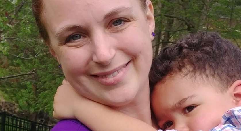 close-up photo of Dayna Edwards and her kid with green trees in the background