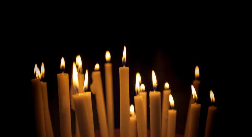 light tall candles close together in a black background 