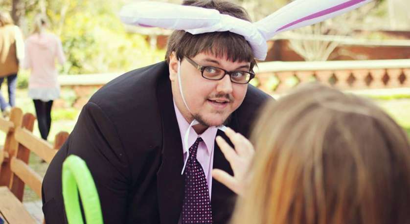 tim atkins our director of lifespand religious education wearing bunny ears in a suit outside surrounded by children